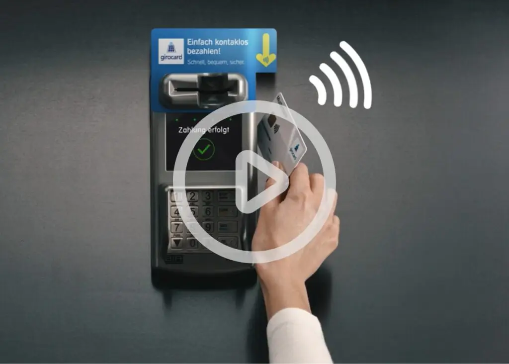 Kontaktloses Bezahlen mit einer girocard an einem modernen Zahlungsterminal, das eine erfolgreiche Transaktion anzeigt. Die Hand hält die Karte nahe am Gerät, während das Display den Status der Zahlung anzeigt.