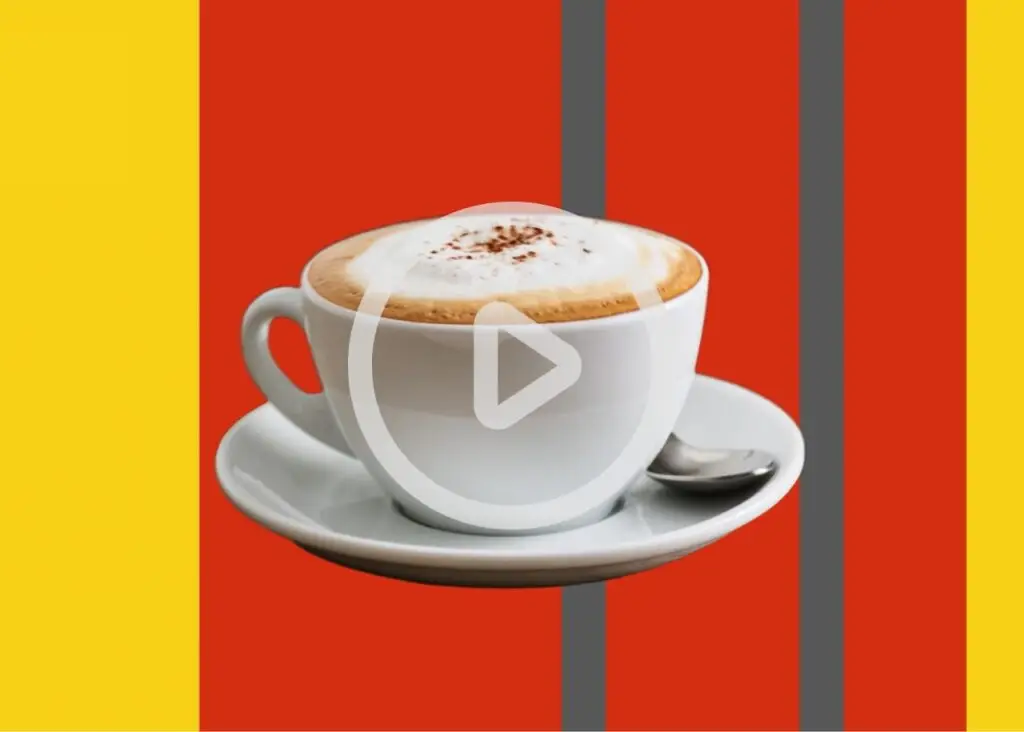 Kaffeetasse mit aufgeschäumter Milch und Zimt auf einem Unterteller vor einem bunten Hintergrund, ideal für Kaffeeliebhaber und Food-Blogger.