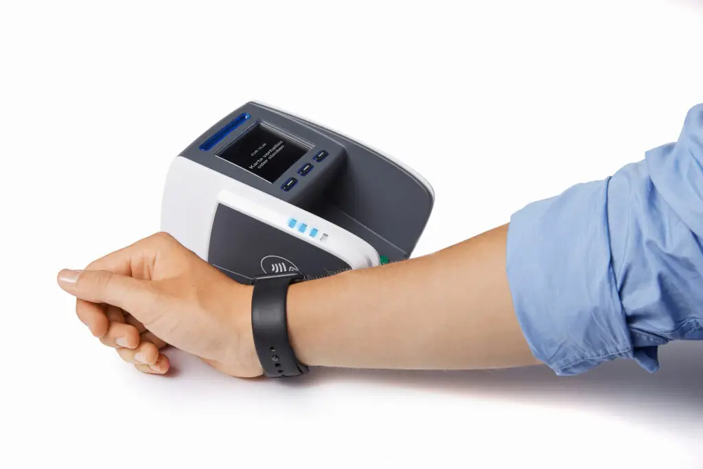 Handgelenk mit Fitness-Armband, das auf ein modernes Messgerät für Gesundheitsdaten gelegt ist, zur Überwachung von Vitalzeichen und Fitnessmetriken.