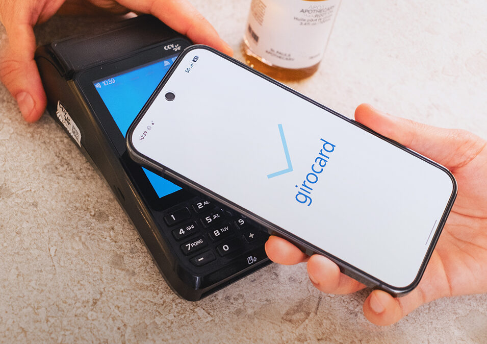Ein Smartphone wird an ein Terminal gehalten; das Display zeigt, dass die Zahlung mit girocard erfolgt ist.